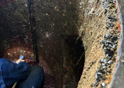 Persona pulisce interno serbatoio arrugginito.